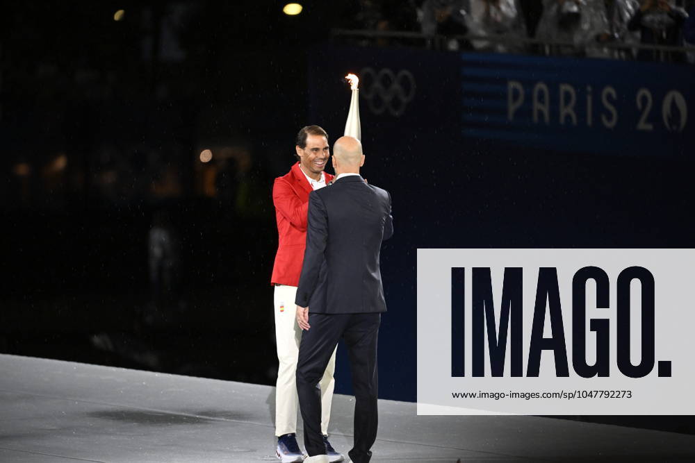 PARIS, FRANKRIKE 20240726 Den tidigare franska fotbollsspelaren Zinedine Zidane lämnar över den olympiska elden till den spanska tennisspelaren Rafael Nadal da sommar-OS i Paris invigs med en ceremoni i Jardins du Trocadà ro samt pa Seine.