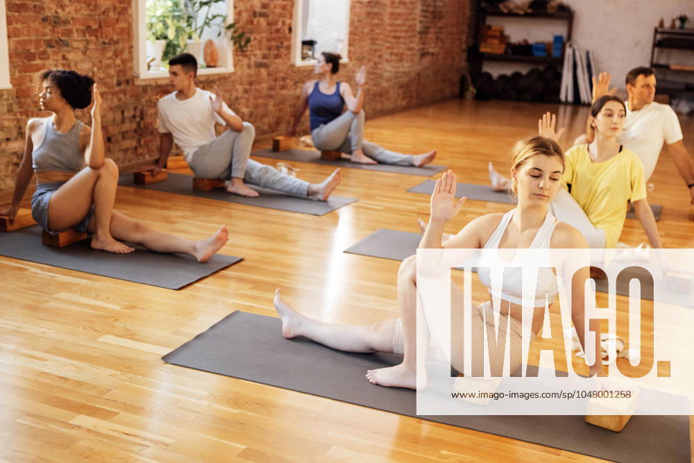 Sporty people of different ages and races practice yoga asanas with instructor in fitness club Sporty people of different ages and races practice yoga asanas with instructor in fitness club. Young multiethnic women and men are sit on mats and stretch in gym with coach. Indoor training. (License=RF) 21634384 ,model released, Symbolfoto
