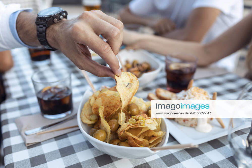 IMAGO Creative, Food, Tapas Cropped image of man having potato chip at cafe model released Symbolfoto property released JSRF01103