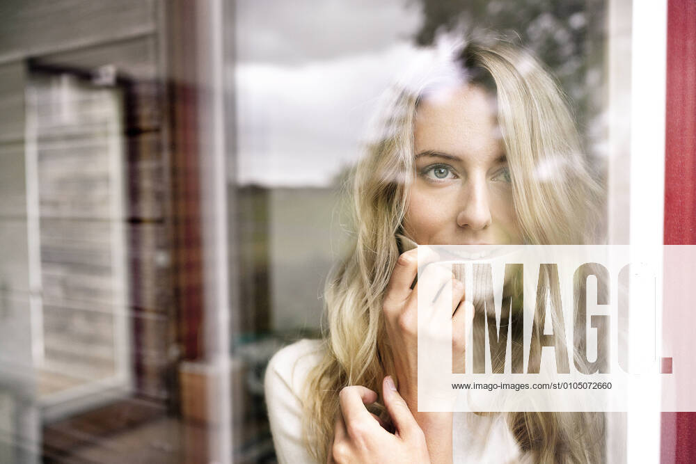 Close-up of businesswoman wearing turtleneck looking through window from office seen through glass model released Symbolfoto property released PESF02070