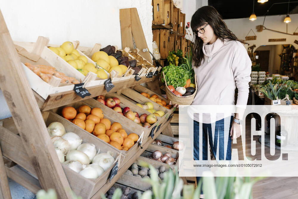 Female customer picking vegetables in basket from grocery store model released Symbolfoto property released RDGF00060