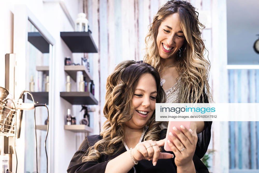 Woman with smartphone and hairdresser making hair styling at salon Granollers, CT, Spain CR_RAFE200930C-404326-01 ,model released, Symbolfoto ,property released