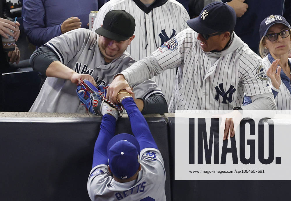 Fans aggressively try wrestle the ball out of Los Angeles Dodgers right fielder Mookie Betts glove who leaps to attempt to catch a foul ball from New York Yankees Gleyber Torres in the first inning in game four of the MLB, Baseball Herren, USA World Series at Yankee Stadium in New York City on Tuesday, October 29, 2024. New York fans interfered with Betts on the play. POY2024S056 JOHNxANGELILLO