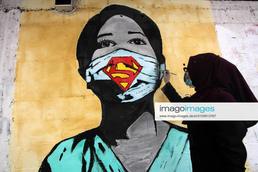 Gaza City, Gaza Strip, Palestinian Territory: Palestinian artists paint a mural, of a medical worker wearing a Supergirl mask to help raise awareness of wearing face masks amid the coronavirus pandemic (COVID-19) crisis, in Gaza city. Gaza City Palestinian Territory - ZUMAap3_ 20201022_zaf_ap3_034