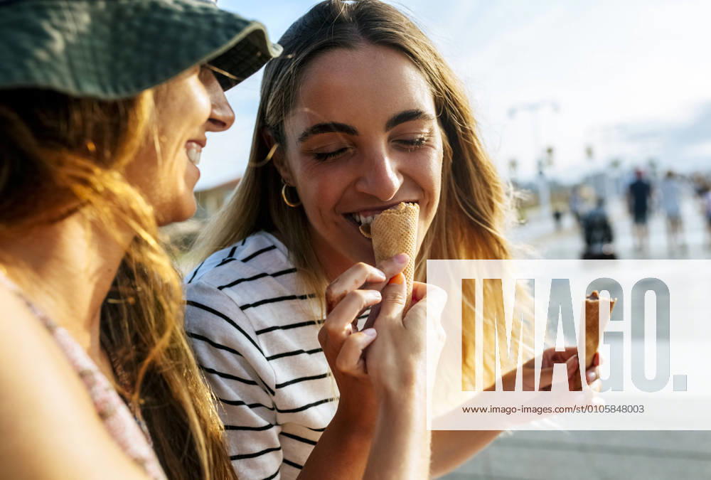 Smiling young woman feeding ice cream to sister while spending enjoying in city model released Symbolfoto MGOF04493