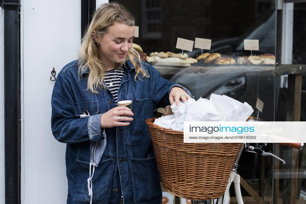Young blond woman standing next to bicycle outside waste free wholefood store. United Kingdom,Young blond woman standing next to bicycle outside waste free wholefood store. Young blond woman standing next to bicycle outside waste free wholefood store.