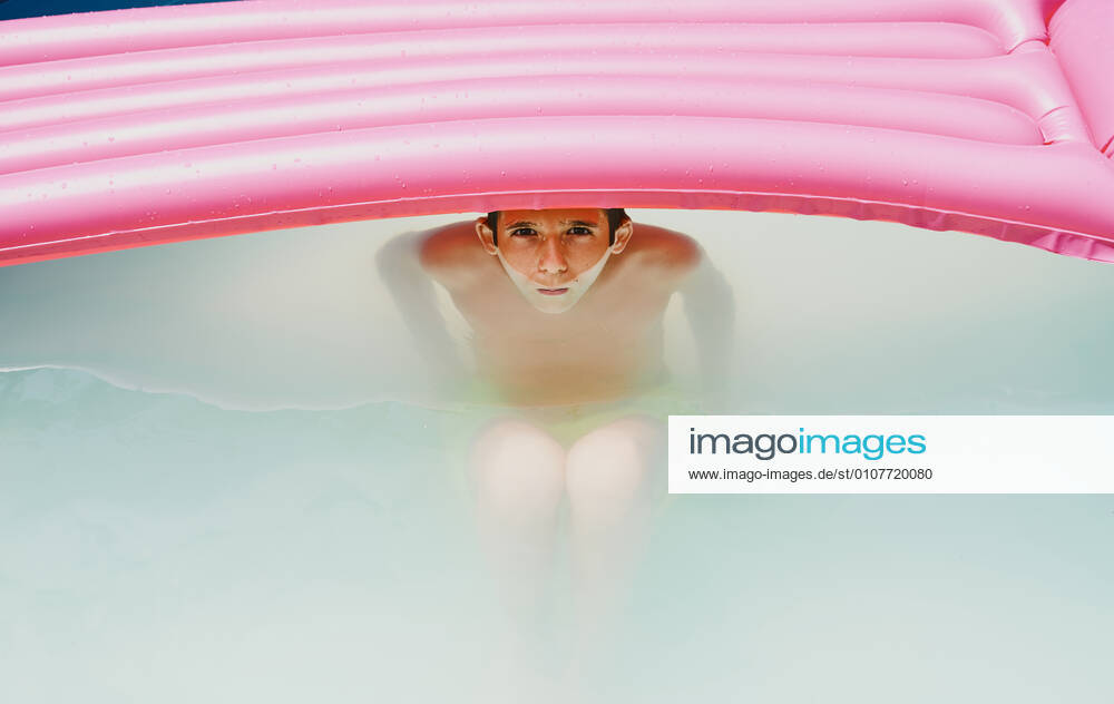 IMAGO Creative: 2021 Favoriten IMAGO Creative: Kraft des Wassers Boy in a pool taking a bath under a pink flat looking at camera. Zaragoza, Aragon, Spain CR_RUBO201207B-575453-01 ,model released, Symbolfoto