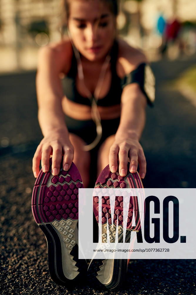 Girl, runner and stretching legs on ground, outdoor and warm up for exercise or fitness training. Female person, earphones and athlete for cardio preparation, muscle flexibility and music for workout. (License=RF) 21844815 ,model released, Symbolfoto