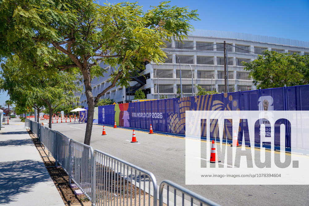 USA: Fussball FIFA World Cup, WM, Weltmeisterschaft, Fussball 2026 WM-Vorbereitung SoFi Stadium (Inglewood, Los Angeles County, Kalifornien): FIFA World Cup 2026 Branding und Sicherheitsinfrastruktur rund um das SoFi Stadium. Absperrgitter, mobile Zäune und Verkehrsleitkegel entlang einer Zufahrtsstraße nahe des WM-Spielorts. FIFA Fussball-Weltmeisterschaft 2026, WM 2026, Veranstaltungsorganisation, Eventmanagement, Sicherheitskonzept, Zugangskontrolle, Akkreditierung, Infrastruktur, Sportgroßereignis, Gastgeberstadt, Los Angeles, Inglewood, Stadionumfeld, Vorbereitung, Logistik, Crowd Management, Verkehrslenkung, Veranstaltungsfläche, Symbolfoto.