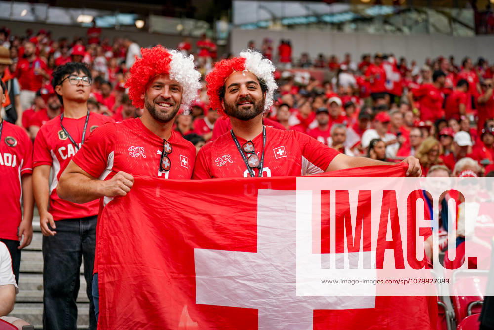 Kanada: Fußball FIFA Weltmeisterschaft 2026 Gruppenphase Schweiz vs Kanada BC Place Stadium (Vancouver, British Columbia): Schweizer Fußballfans, Fans, Fan-Porträt, zwei Supporter mit Schweiz-Fahne, Nationalflagge Schweiz, rot-weiße Perücken, SFV-Trikot, Schweizerischer Fussballverband, Gesichtsausdruck, Lächeln, Fankultur, Fußballbegeisterung, Zuschauer, Tribüne, Stadionatmosphäre, Fanblock, Anhänger, Support, internationale Fans, Gruppenfoto, Portrait, Fahne, Nationalstolz, Sportevent, WM-Stimmung, Publikum, Freizeit, Menschenmenge, Schweiz, Fußball, Emotionen, rote Fanbekleidung.