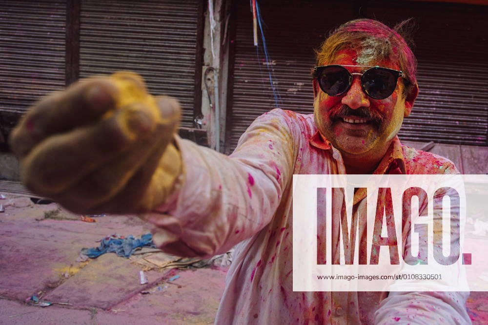 Content Indian male in clothes colored with paint standing on street during Holi festival