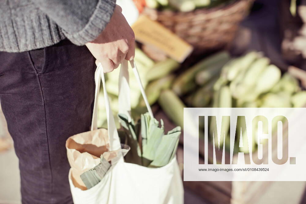 Midsection of man carrying vegetable bag in market , model released