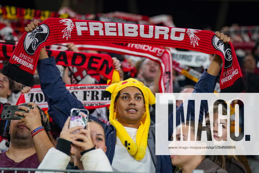 Deutschland: Fussball UEFA Conference League 2026 - 2027, 1. Spieltag - SC Freiburg vs FK Jablonec - Europa-Park-Stadion (Freiburg): Fan des SC Freiburg mit gelber Pikachu-Mütze hält einen rot-schwarzen Fanschal mit der Aufschrift FREIBURG und Vereinswappen über den Kopf. Porträt eines Anhängers auf der Tribüne des Europa-Park-Stadions beim UEFA Conference League-Spiel gegen FK Jablonec. SC Freiburg, Fussball, Europapokal, Fans, Zuschauer, Fankultur, Fanschal, Fanartikel, Merchandising, Pikachu, Pokà mon, Kostüm, Verkleidung, Vereinsfarben, Heimfans, Stimmung, Begeisterung, Supporter, Smartphone, Stadion.