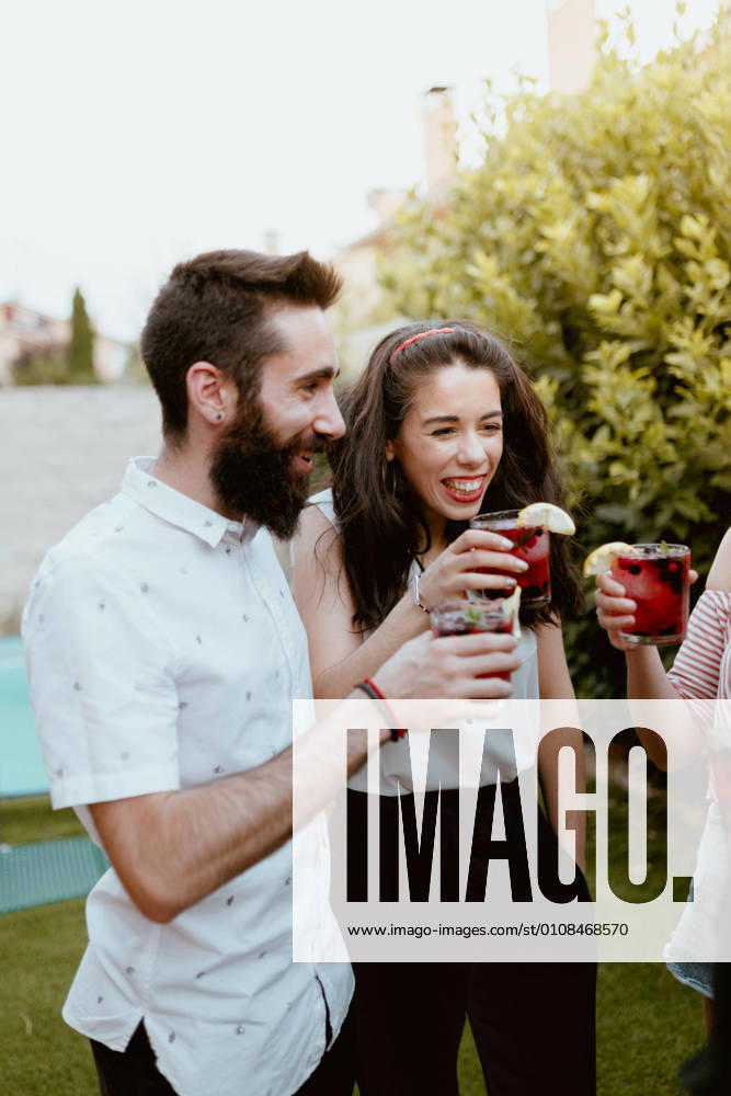 Group of cheerful friends clinking glasses at party