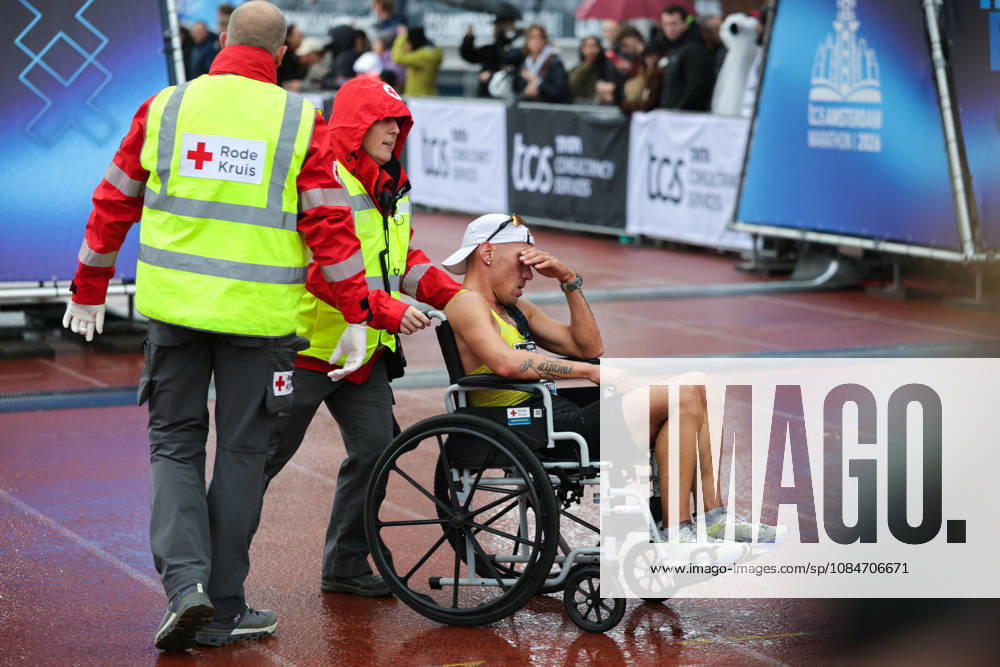 18th October 2026; Amsterdam, Netherlands; TCS Amsterdam Marathon; A runner is wheeled off the track in the Olympic Stadium by Red Cross first aid staff AnthonyxBenoit