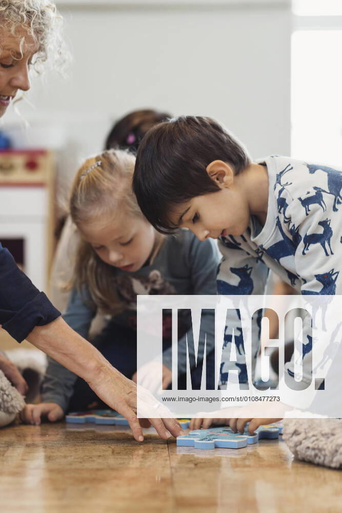 IMAGO Creative: Jahreszeit Winter, Fantasievoll drinnen spielen Teacher and children playing jigsaw puzzle , model released, property released