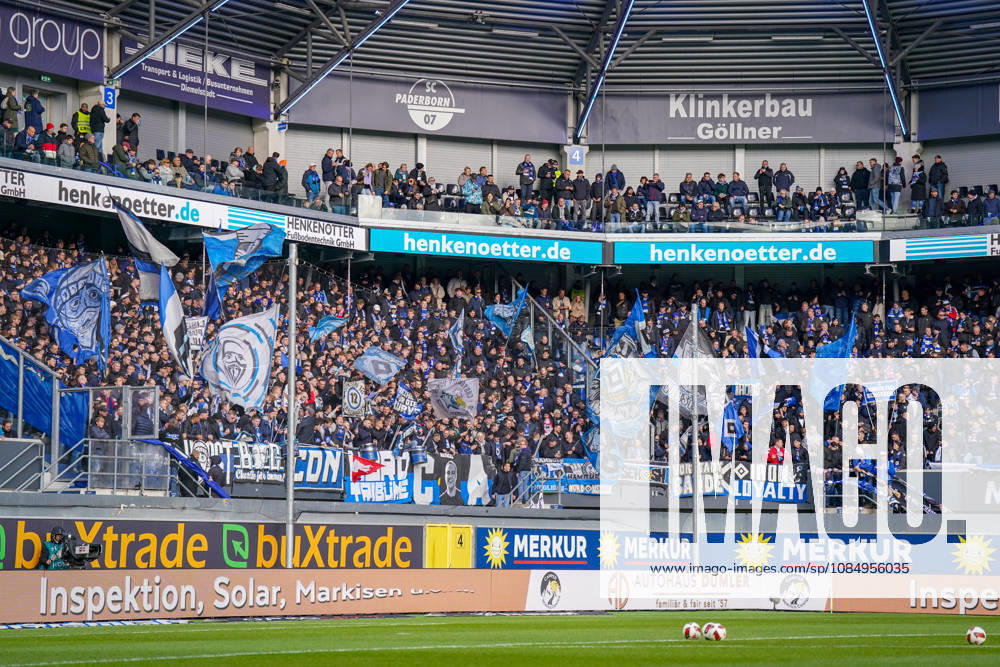 Deutschland: Fussball Bundesliga 2026 - 2027, 7. Spieltag - SC Paderborn vs Hamburger SV - Home-Deluxe-Arena (Paderborn): Fans und Auswärtsfans des Hamburger SV (HSV) auf der Gästetribüne der Home-Deluxe-Arena in Paderborn. Dicht besetzter Gästeblock mit zahlreichen blau-weiss-schwarzen Fahnen, Fanbannern, Transparenten und Schals. Fankultur, Ultras, organisierte Fanszene, Auswärtsspiel, Fussball, Bundesliga, Zuschauer, Stimmung, Support, Fanblock, Tribüne, Totale, Stadion, Sportstätte, Sicherheitszaun, Werbung, Sponsoren, Werbebanden, Merkur, buXtrade, HENKENOTTER.
