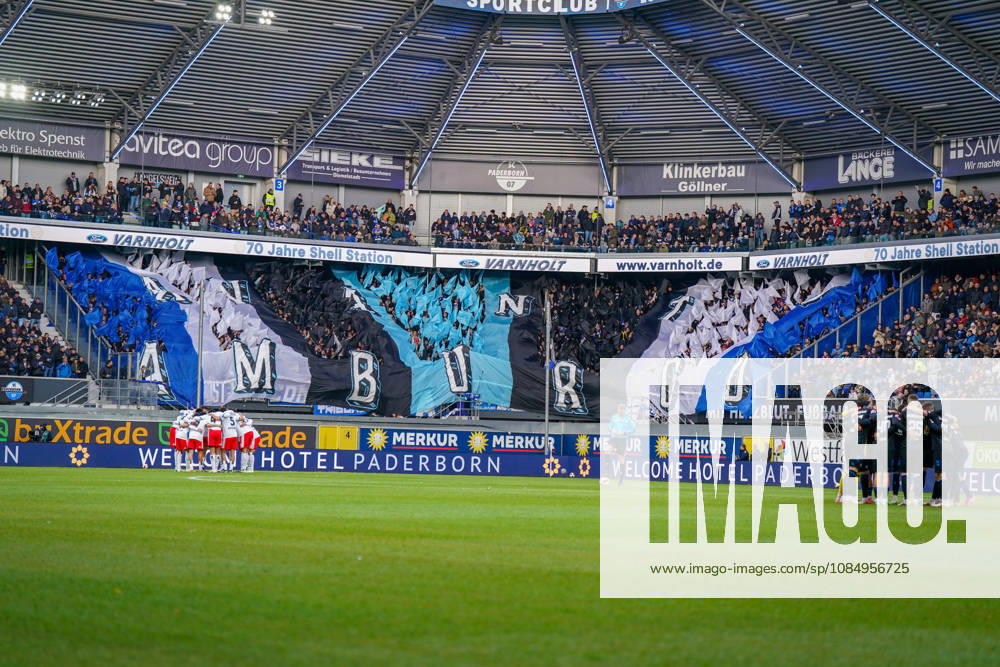 Deutschland: Fussball Bundesliga 2026 - 2027, 7. Spieltag - SC Paderborn vs Hamburger SV - Home-Deluxe-Arena (Paderborn): Innenansicht der Home-Deluxe-Arena in Paderborn mit grosser blau-schwarz-weisser Choreographie der Heimfans des SC Paderborn 07, Schriftzug HAMBURG. Fans, Ultras, Fanchoreo, Fanszene, Fahnen, Zuschauer, Tribüne, Fanblock, Stimmung, Mannschaftskreise von SC Paderborn und Hamburger SV vor Spielbeginn, Fussball, Bundesliga, Stadion, Sportstätte, Totale, Spielfeld, Schiedsrichter, Flutlicht, Werbung, Sponsoren, Werbebanden, Merkur, buXtrade, Varnholt, Welcome Hotel.