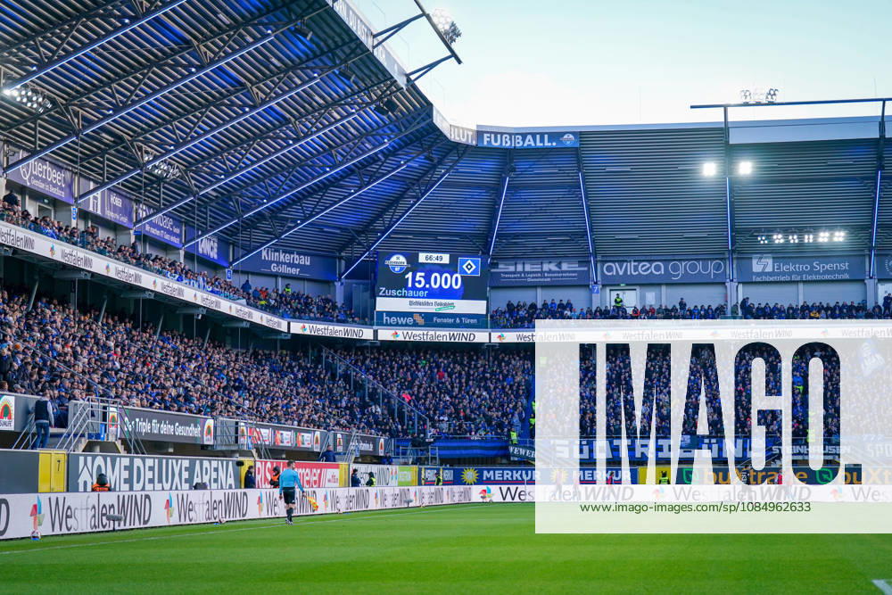 Deutschland: Fussball Bundesliga 2026 - 2027, 7. Spieltag - SC Paderborn vs Hamburger SV - Home-Deluxe-Arena (Paderborn): Totale der Home-Deluxe-Arena in Paderborn, Innenansicht mit voll besetzten Tribünen und Stadionanzeige 15.000 Zuschauer beim Bundesligaspiel SC Paderborn 07 gegen Hamburger SV (HSV). Ausverkauftes Stadion, Zuschauerzahl, Fans, Fankurve, Stadiondach, Flutlicht, Spielfeld, Schiedsrichterassistent, Anzeigetafel, Sportstätte, Fussball, Bundesliga, Werbung, Sponsoren, Werbebanden, WestfalenWIND, Merkur, buXtrade, avitea group, Klinkerbau Göllner.