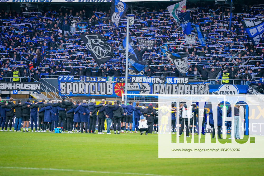 Deutschland: Fussball Bundesliga 2026 - 2027, 7. Spieltag - SC Paderborn vs Hamburger SV - Home-Deluxe-Arena (Paderborn): Heimsieg des SC Paderborn 07 gegen den Hamburger SV (HSV). Spieler, Trainer und Betreuer feiern nach Spielende gemeinsam mit den Heimfans vor der Fankurve der Home-Deluxe-Arena. Siegesfeier, Jubel, Mannschaft, Mannschaftsfoto von hinten, Schulterschluss, Fans, Ultras, Zuschauer, Tribüne, Fahnen, Schals, Fangesänge, Emotionen, Bundesliga, Fussball, Heimsieg, Sportstätte, Innenansicht, Totale, Hintertorperspektive, Tor, Fanbanner, Fankultur, Zusammenhalt.