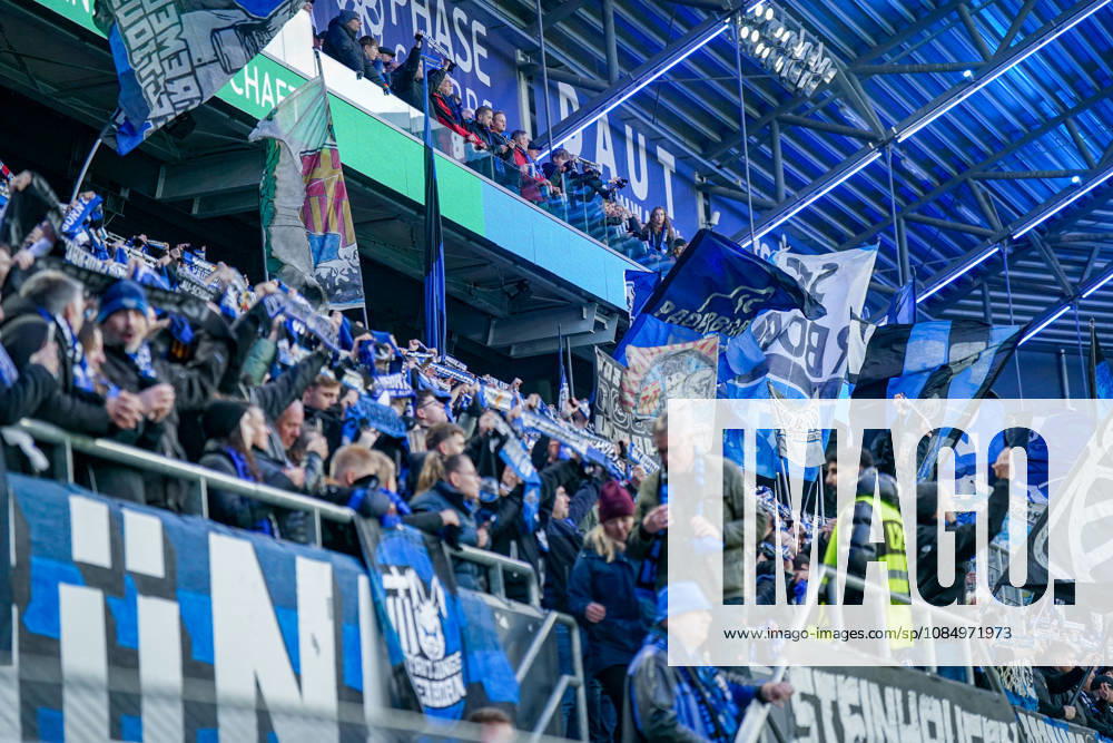 Deutschland: Fussball Bundesliga 2026 - 2027, 7. Spieltag - SC Paderborn vs Hamburger SV - Home-Deluxe-Arena (Paderborn): Heimfans des SC Paderborn 07 feiern auf der Tribüne der Home-Deluxe-Arena den Heimsieg gegen den Hamburger SV (HSV). Zahlreiche grosse blau-schwarz-weisse Fahnen mit Vereinswappen und Fanmotiven. Fans, Ultras, Fanszene, Fankultur, Fankurve, Fanblock, Zuschauer, Fahnenmeer, Jubel, Siegesfeier, Stimmung, Emotionen, Support, Fangesänge, Tribüne, Bundesliga, Fussball, Sportstätte, Innenansicht, Stadiondach, Flutlicht, Sicherheitsdienst, Ordnungsdienst.