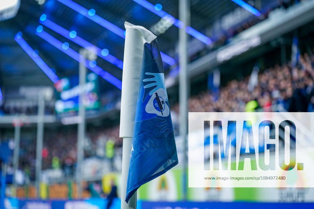 Deutschland: Fussball Bundesliga 2026 - 2027, 7. Spieltag - SC Paderborn vs Hamburger SV - Home-Deluxe-Arena (Paderborn): Detailaufnahme einer blau-weissen Eckfahne mit Vereinswappen des SC Paderborn 07 in der Home-Deluxe-Arena. Fussball, Bundesliga, SC Paderborn gegen Hamburger SV, HSV, Eckball, Eckstoss, Spielfeld, Spielfeldbegrenzung, Spielausrüstung, Equipment, Vereinslogo, Vereinsfarben, Heimspiel, Sportstätte, Stadion, Innenansicht, Nahaufnahme, selektive Schärfe, Zuschauer, Fans, Tribüne, Stadiondach, Flutlicht, LED-Beleuchtung, Werbung, Werbebanden.