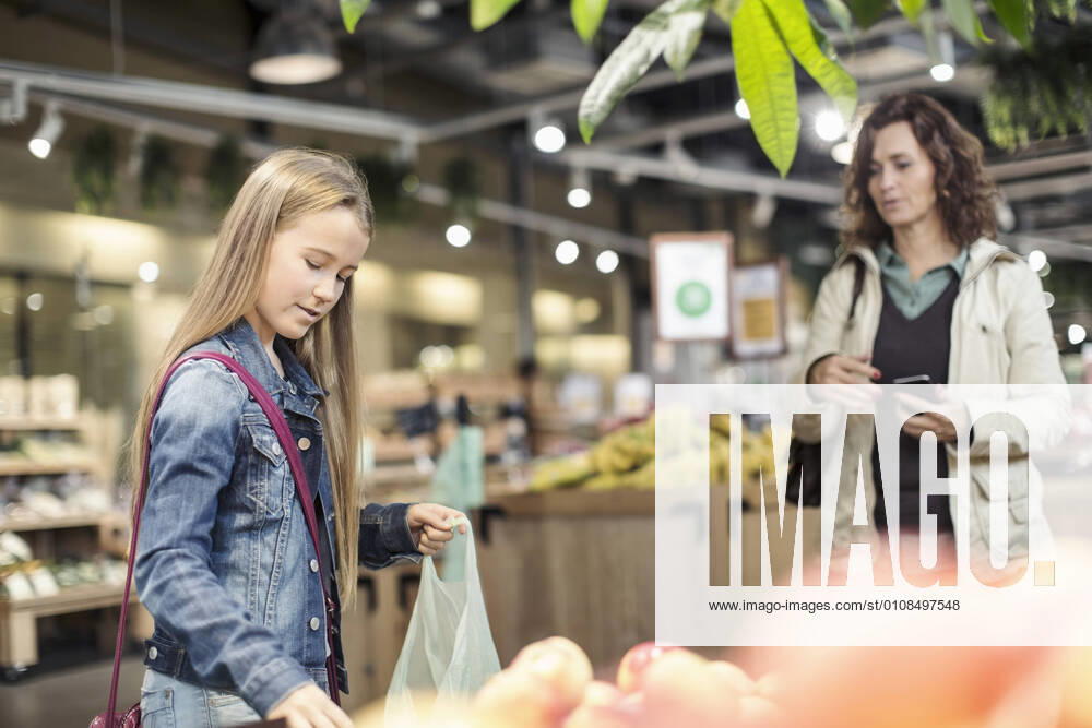 Mother looking at daughter buying apples in supermarket , model released, property released