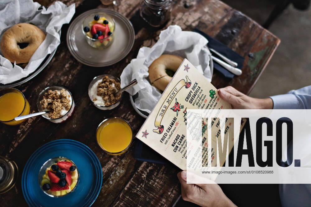 IMAGO Creative: Landleben - Essen Midsection of man holding menu while having brunch at dining table , model released, property released