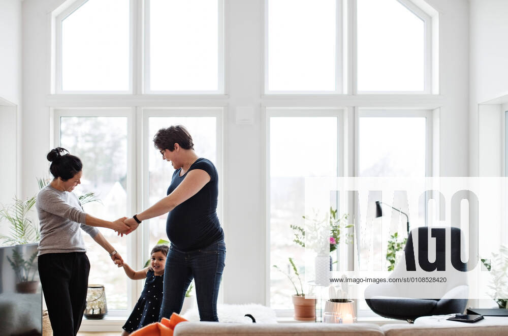 IMAGO Creative: Pride Month 2022, Engagement der Jugendlichen Mothers and daughter holding hands while playing in living room at home , model released, property released