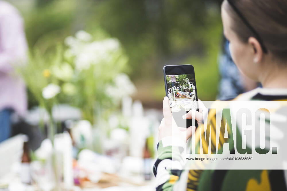 IMAGO Creative: Landleben - Essen Cropped image of woman photographing dining table through mobile phone in backyard , model released, property released