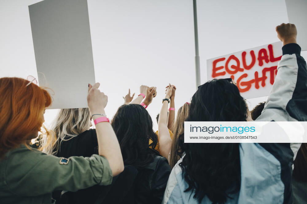 Rear view of women protesting for equal rights against sky in summer , model released
