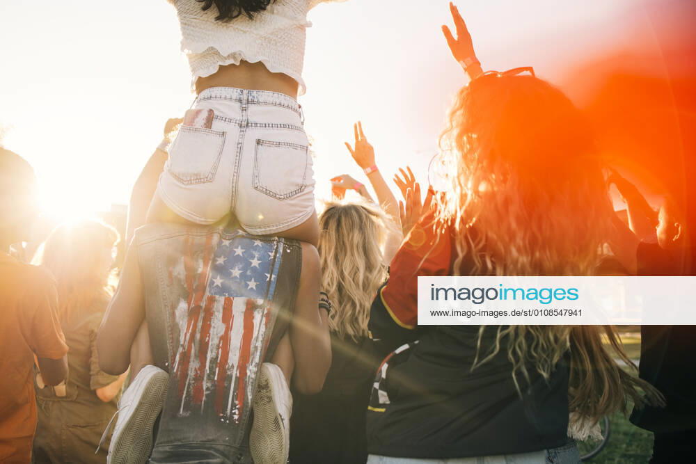 Man carrying friend on shoulder while enjoying in crowd at music event , model released