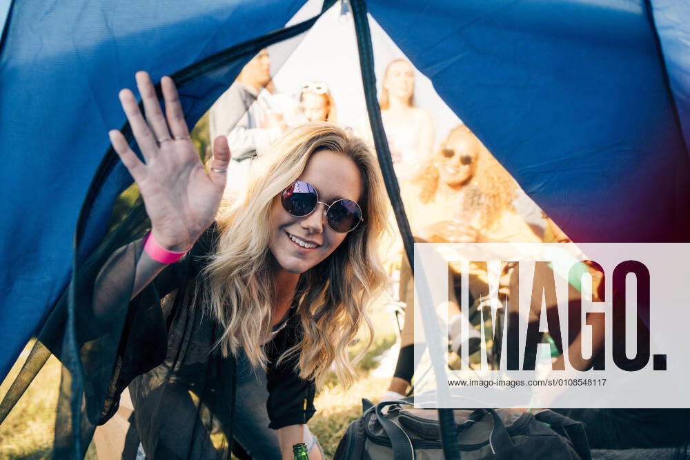 Portrait of smiling woman with friends looking in tent at festival , model released