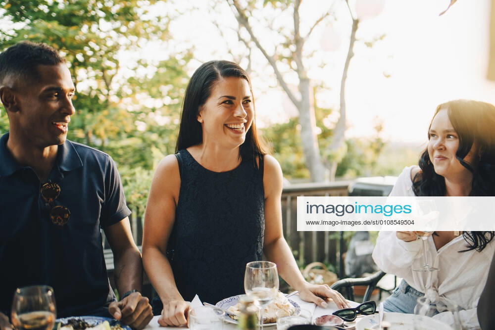 Smiling male and female friends enjoying food at dining table in dinner party , model released, property released