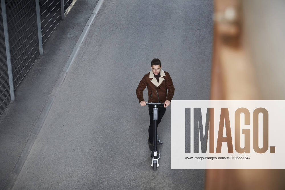 IMAGO Creative: Corporate: Klimaschutz, Digitalisierung und Urbanisierung High angle view of teenage boy riding electric push scooter on street in city , model released