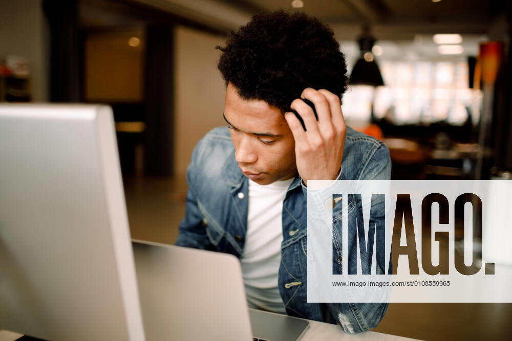 IMAGO Creative: Kreative Renaissance -- der junge Entrepreneur Worried male professional using laptop while sitting at office desk , model released, property released