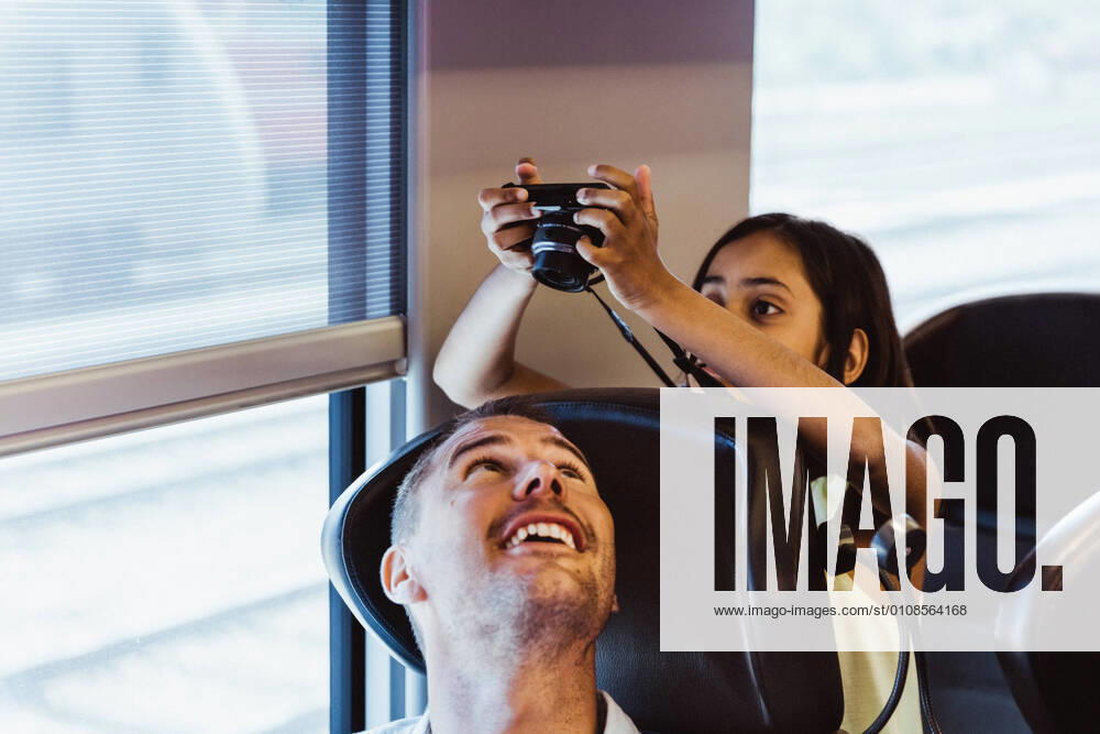 IMAGO Creative: Welttourismustag am 27. September Girl photographing father with camera while sitting in train , model released, property released