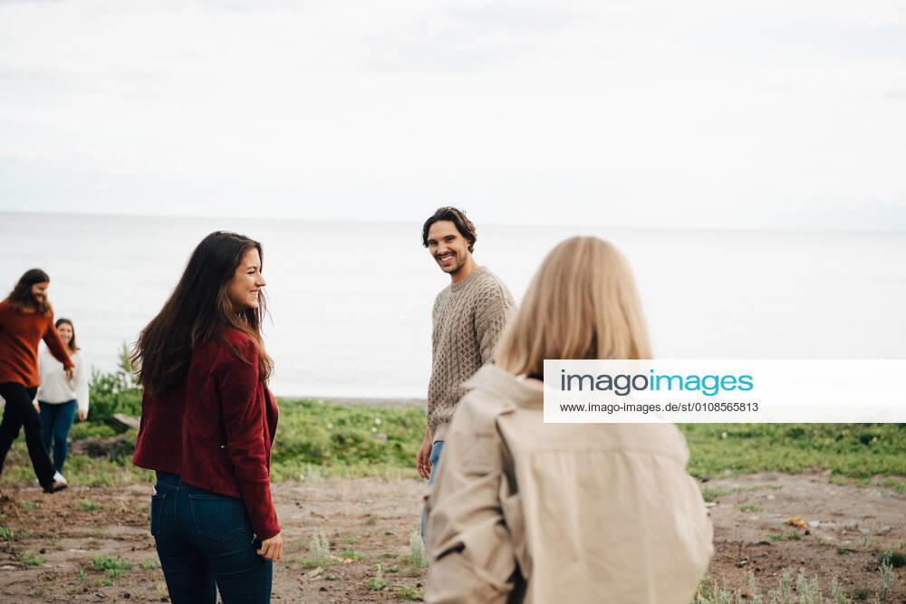 Male and female friends spending leisure time at beach against sky , model released