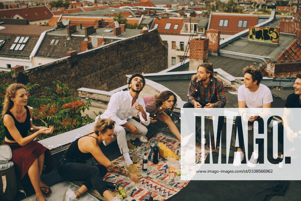 IMAGO Creative, Urban Lifestyle IMAGO Kreativ: Urbane Kultur - Sommer auf den Dächern Cheerful male and female friends enjoying on terrace during rooftop party , model released, property released