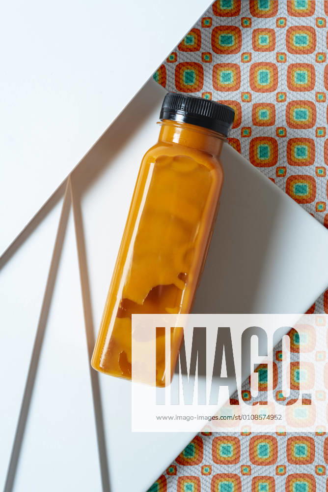 Mango and pumpkin smoothie bottle over retro style geometric textures. From above, Model released, Property released