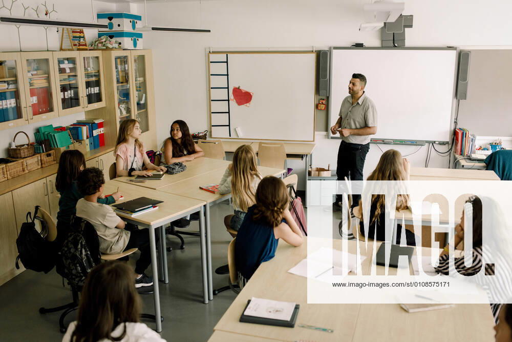 Male tutor teaching students in classroom , model released, property released