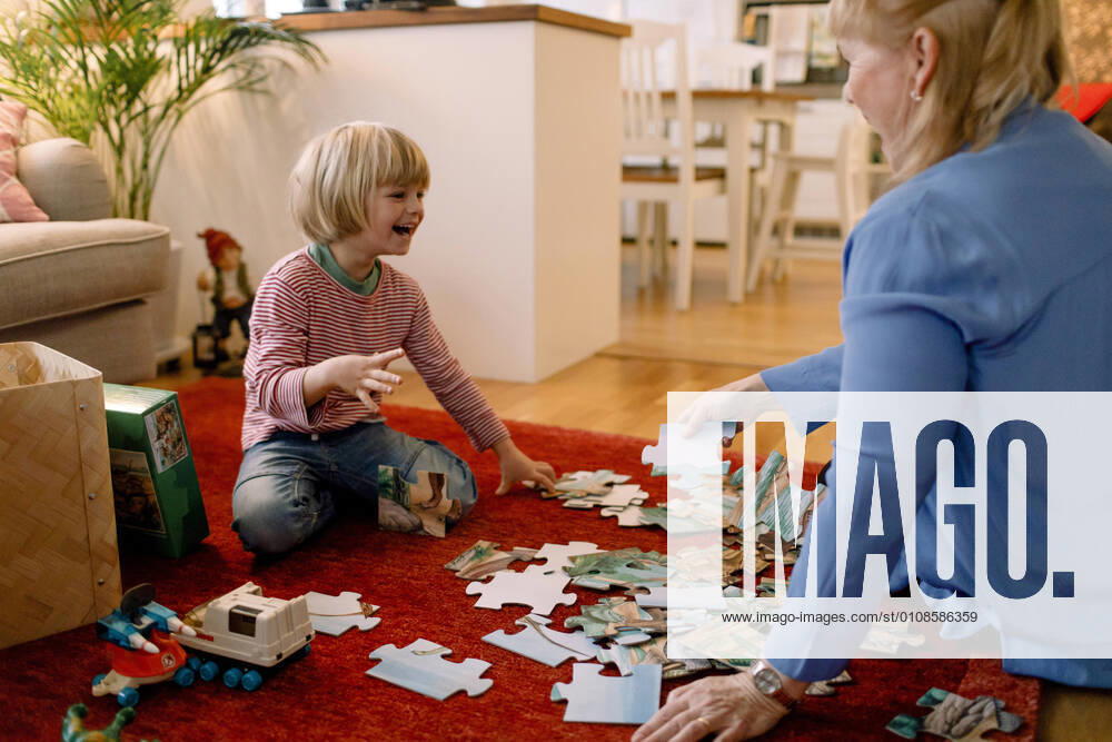IMAGO Creative: Jahreszeit Winter, Fantasievoll drinnen spielen Cheerful boy playing jigsaw puzzle with grandmother in living room Sweden, Stockholm, model released, property released