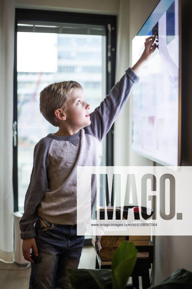Boy touching digital display of smart television set at modern home Sweden, Stockholm, model released, property released