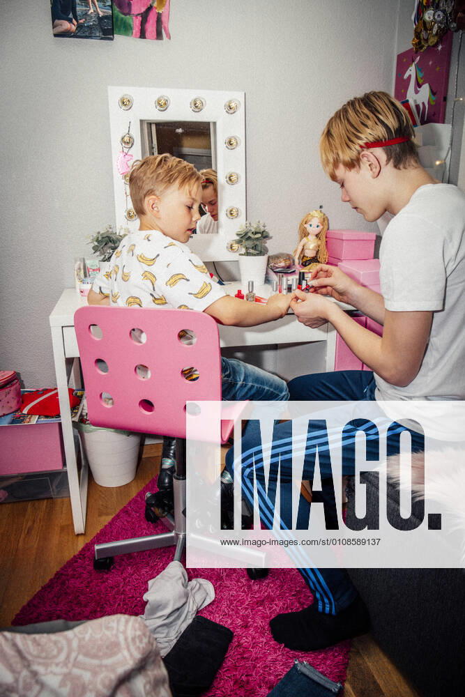 IMAGO Creative: Jahreszeit Winter, Fantasievoll drinnen spielen Boy applying nail polish on brother at home Sweden, Stockholm, model released, property released