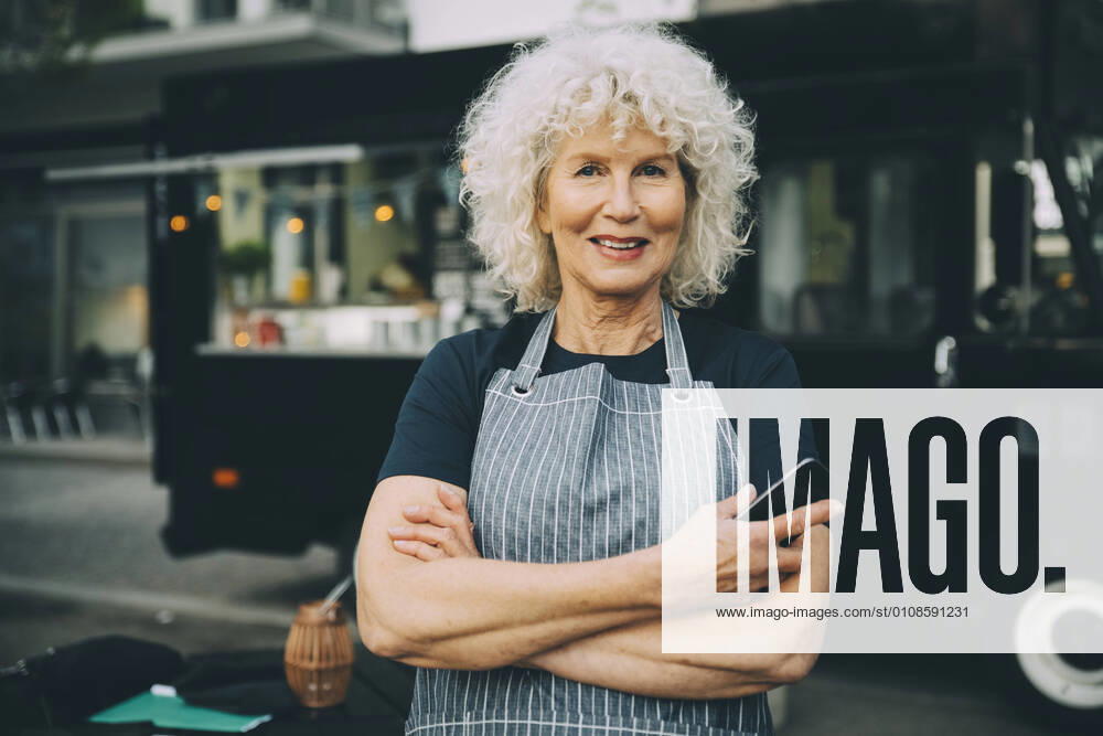 Portrait of senior owner with smart phone standing against food truck in city Sweden, Stockholm, model released, property released