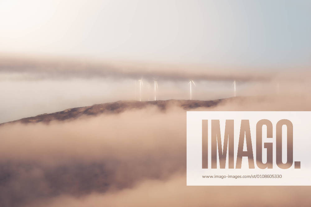 IMAGO Creative: Klimawandel - Zukunft und Innovation Windmills of modern wind power station located on hill in misty morning in countryside