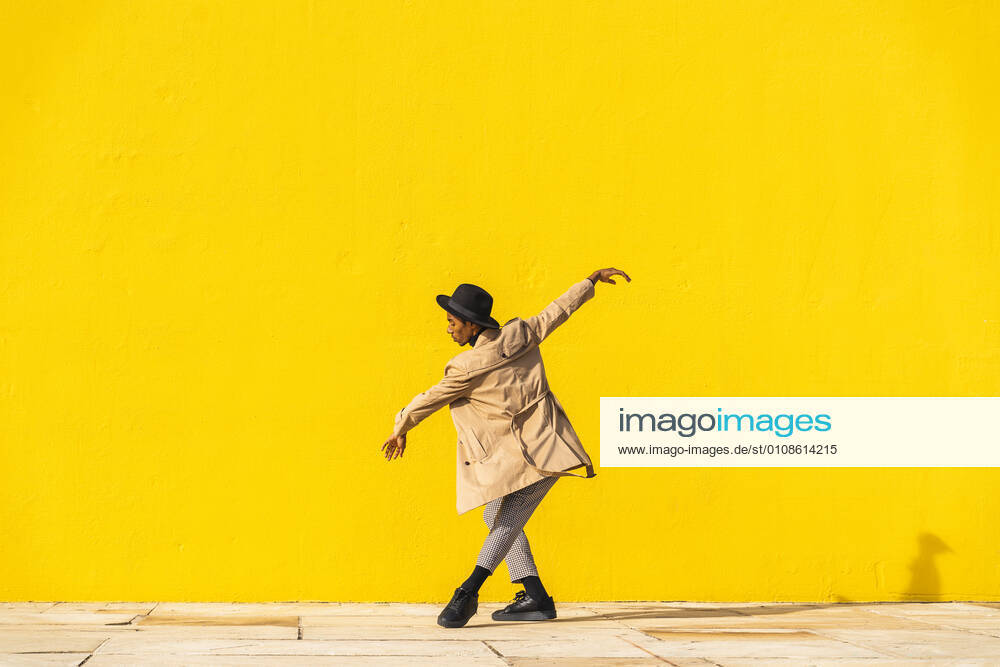 Young man dancing in front of yellow wall model released Symbolfoto AFVF04558