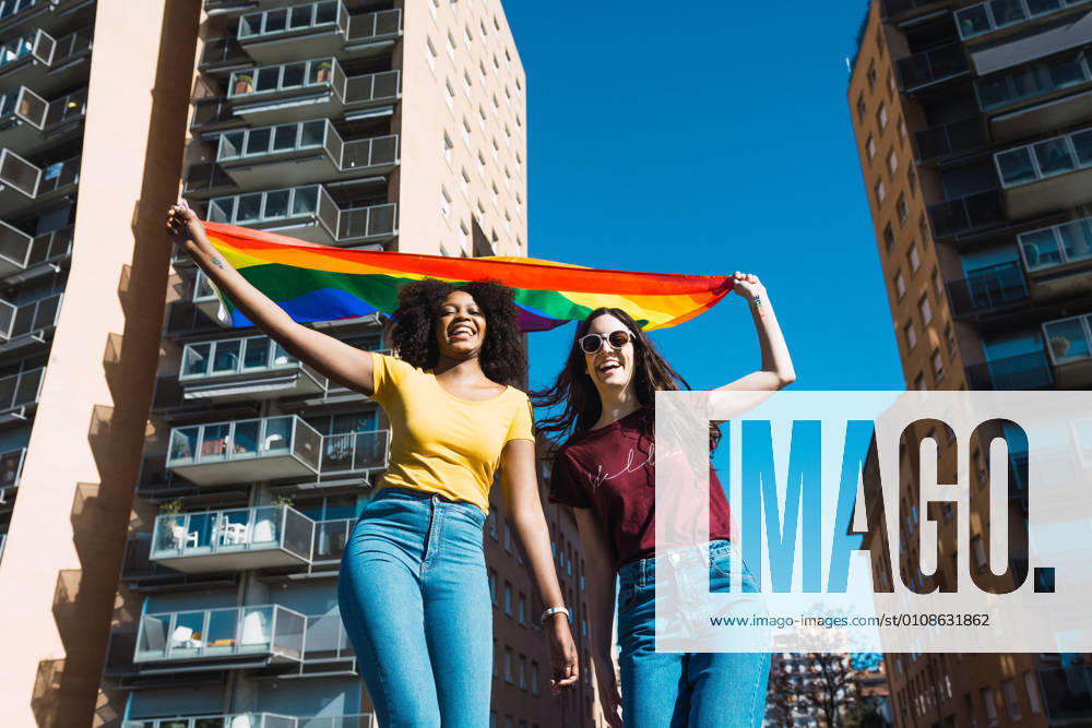 IMAGO Creative: Pride Month 2022, Engagement der Jugendlichen Lesbian couple celebrating with LGBT flag on gay pride day