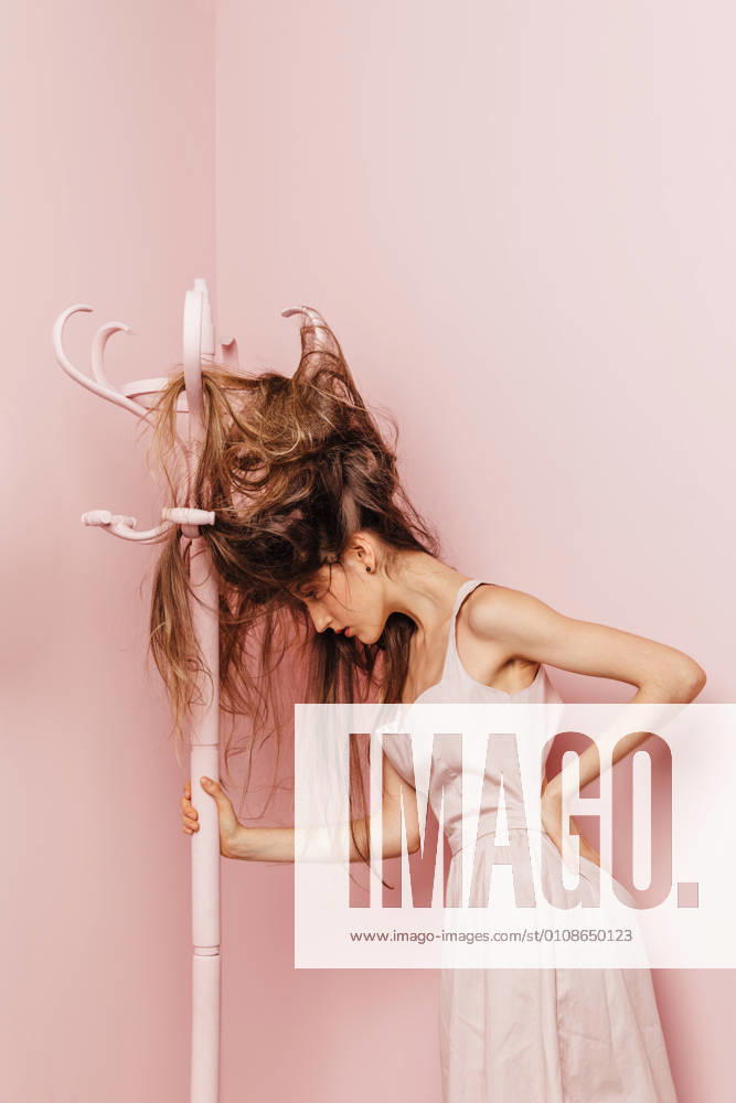 Front view of a teenage girl with tangled hairs on pink background, Model released, Property released
