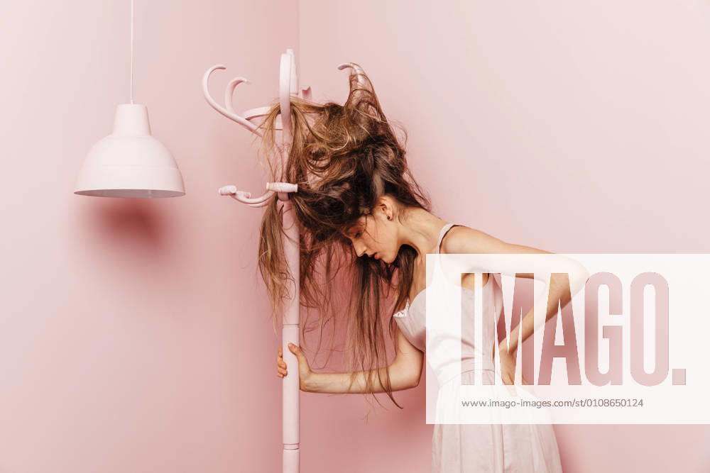 Front view of a teenage girl with tangled hairs on pink background, Model released, Property released